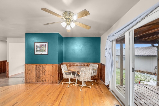 living area featuring ceiling fan, wood walls, and light hardwood / wood-style flooring