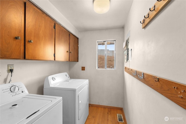 laundry area with washer and dryer, light hardwood / wood-style floors, and cabinets