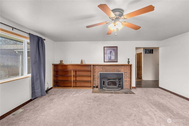 unfurnished living room featuring ceiling fan, light colored carpet, and a wood stove