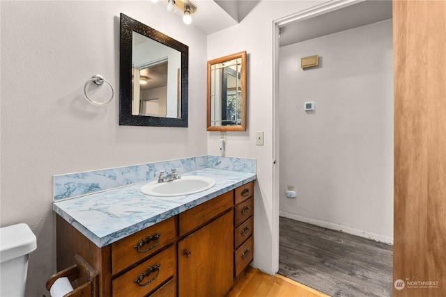 bathroom featuring vanity, wood-type flooring, and toilet