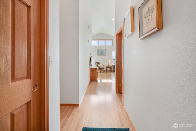 hall with light hardwood / wood-style flooring and vaulted ceiling