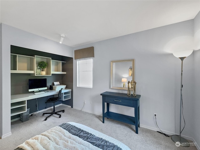 bedroom with built in desk and light carpet