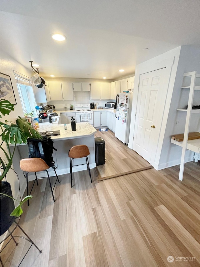 4105 Stone Way N, Seattle, WA 98103 - kitchen with light hardwood / wood-style floors, white cabinetry, white appliances, and a breakfast bar area