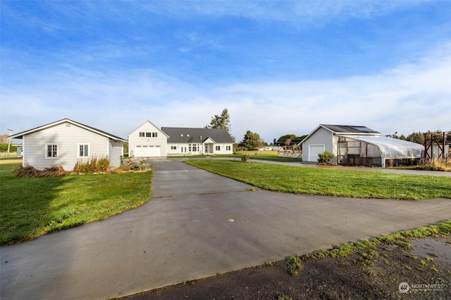 view of front of house featuring a garage, an outbuilding, and a front yard