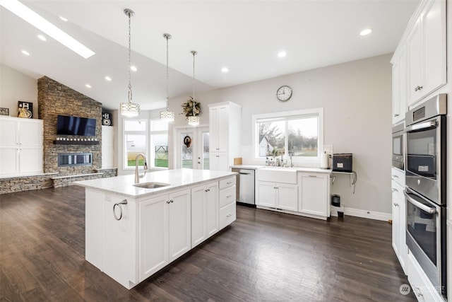 kitchen featuring white cabinets, appliances with stainless steel finishes, a kitchen island with sink, and sink