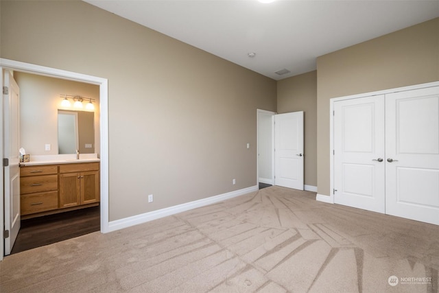 unfurnished bedroom featuring carpet flooring, ensuite bath, a closet, and sink