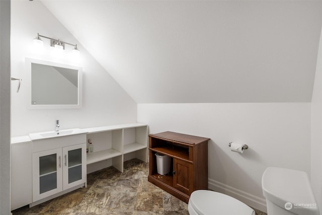 bathroom with vanity, toilet, and lofted ceiling