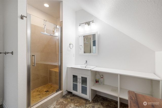 bathroom with a textured ceiling, a shower with door, vanity, and lofted ceiling