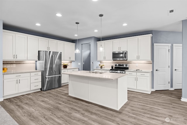 kitchen with white cabinets, appliances with stainless steel finishes, decorative light fixtures, and sink