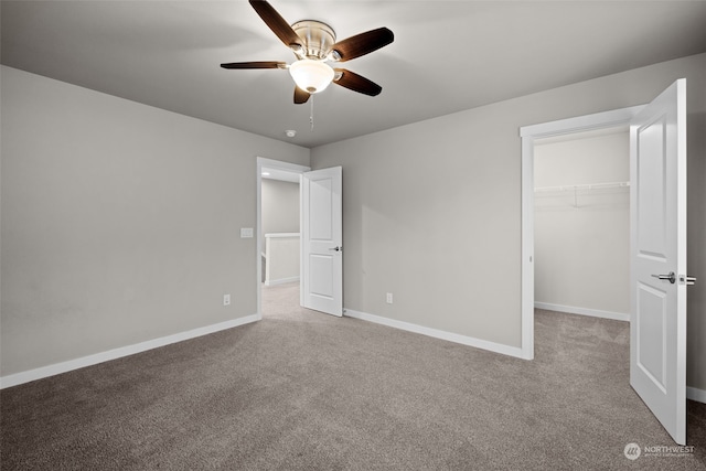 unfurnished bedroom with light carpet, a walk in closet, a closet, and ceiling fan