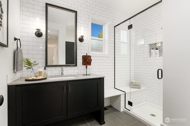 bathroom featuring a shower with door, tile walls, vanity, and tile patterned flooring