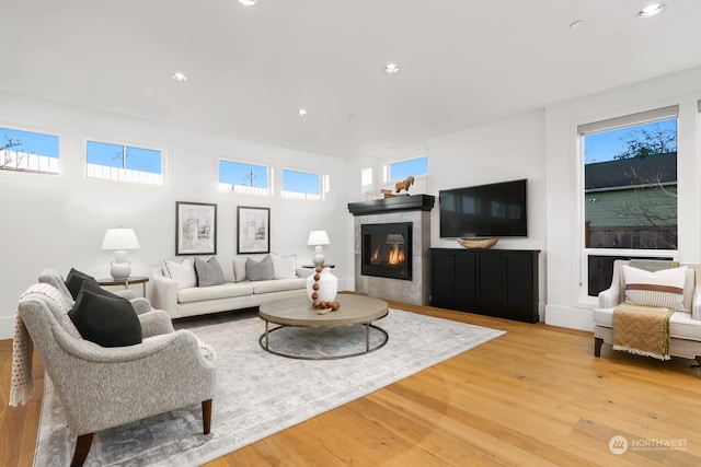 living room with a tiled fireplace and light wood-type flooring