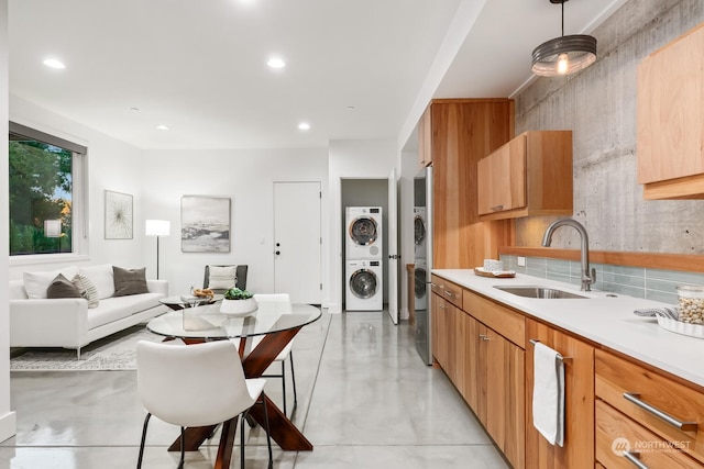 kitchen featuring sink, stacked washer and dryer, and hanging light fixtures