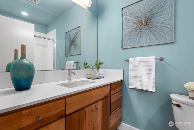 bathroom featuring toilet, a shower with shower door, and vanity