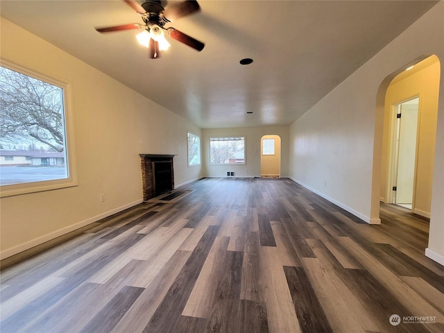 unfurnished living room featuring ceiling fan, dark hardwood / wood-style flooring, and a brick fireplace