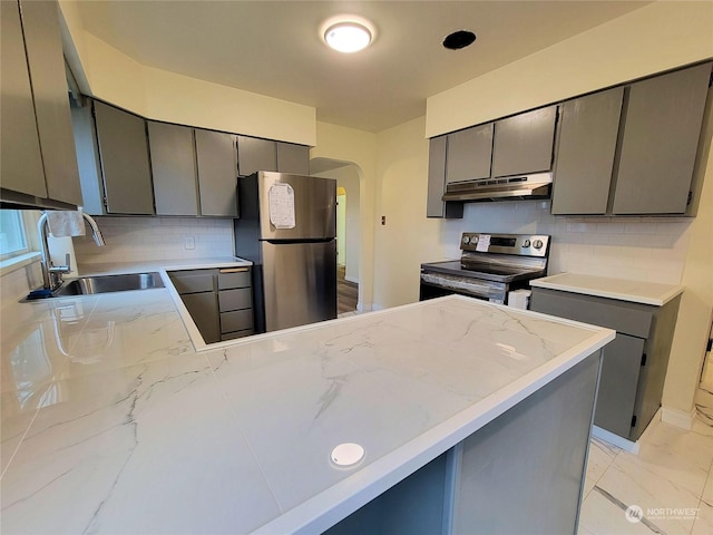 kitchen featuring kitchen peninsula, decorative backsplash, stainless steel appliances, sink, and gray cabinets