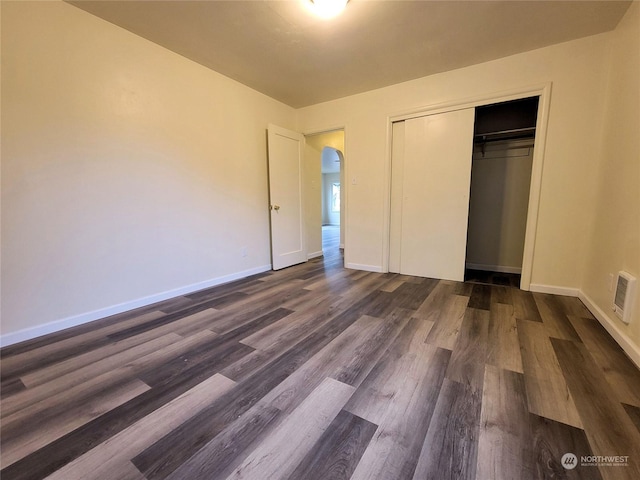 unfurnished bedroom featuring dark wood-type flooring and a closet