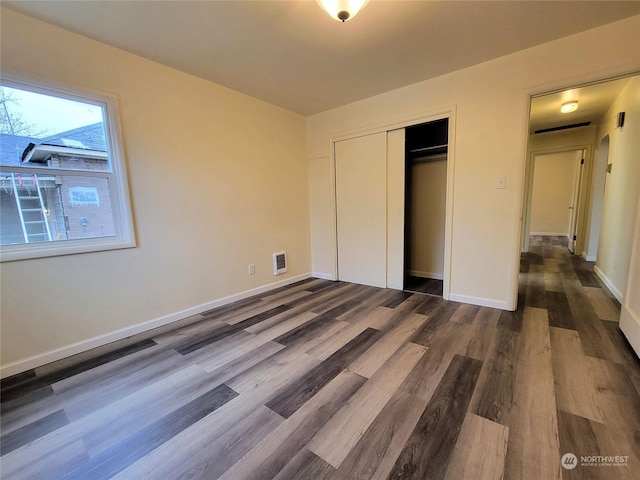 unfurnished bedroom with dark hardwood / wood-style flooring and a closet