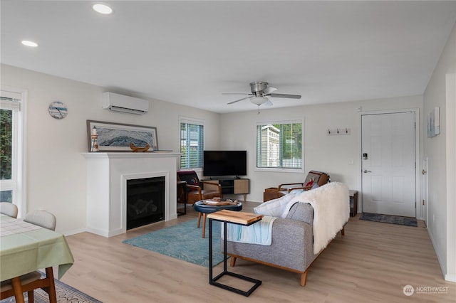 living room with light hardwood / wood-style floors, ceiling fan, and an AC wall unit