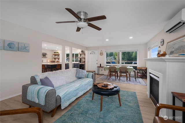 living room with an AC wall unit, ceiling fan, and light hardwood / wood-style floors