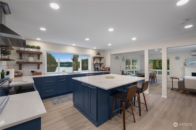 kitchen featuring light hardwood / wood-style flooring, sink, a kitchen bar, a kitchen island, and a water view