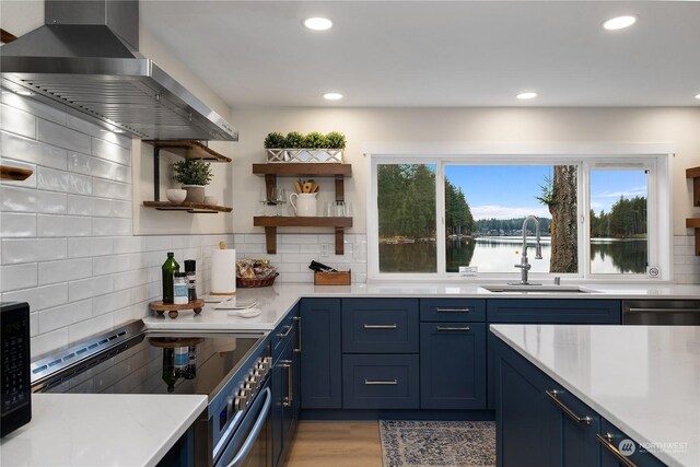 kitchen with electric range, island exhaust hood, a water view, sink, and backsplash