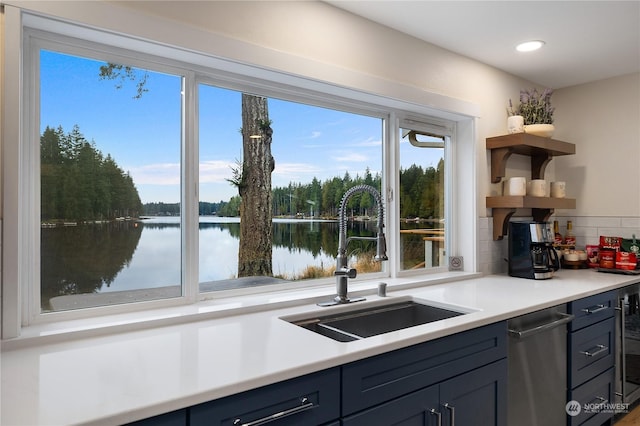 kitchen featuring sink, blue cabinetry, tasteful backsplash, and a water view