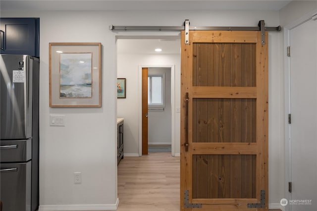 corridor featuring light wood-type flooring and a barn door