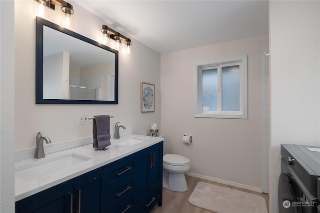 bathroom with toilet, walk in shower, vanity, washer / dryer, and hardwood / wood-style flooring