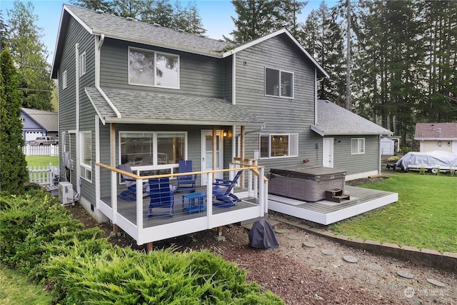 back of house with a lawn, a hot tub, and a wooden deck