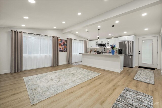 kitchen featuring a kitchen island with sink, white cabinets, lofted ceiling with beams, appliances with stainless steel finishes, and decorative light fixtures