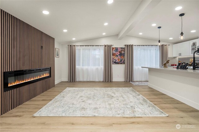 interior space featuring lofted ceiling with beams, white cabinetry, pendant lighting, and light wood-type flooring