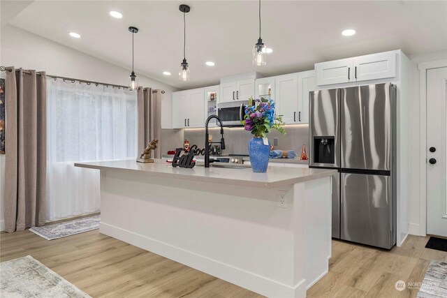 kitchen with white cabinetry, stainless steel appliances, a kitchen island with sink, and vaulted ceiling