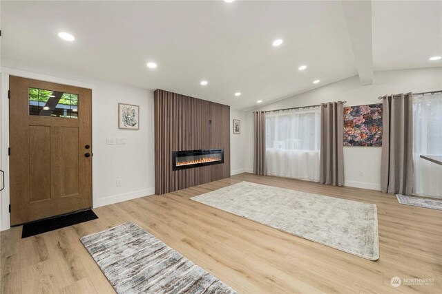 unfurnished living room featuring lofted ceiling with beams, light wood-type flooring, and a fireplace