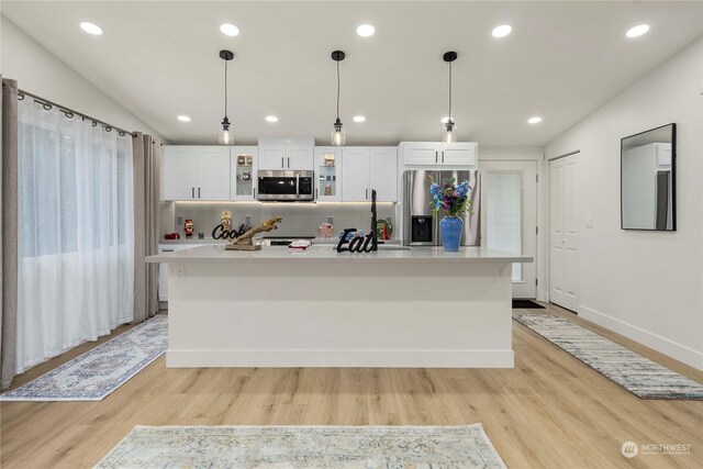 kitchen with a center island, light hardwood / wood-style floors, stainless steel appliances, and hanging light fixtures