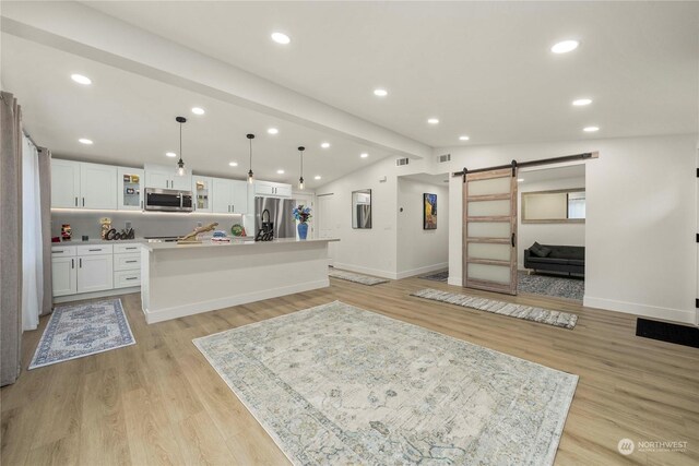 kitchen featuring stainless steel appliances, pendant lighting, lofted ceiling with beams, a barn door, and a kitchen island