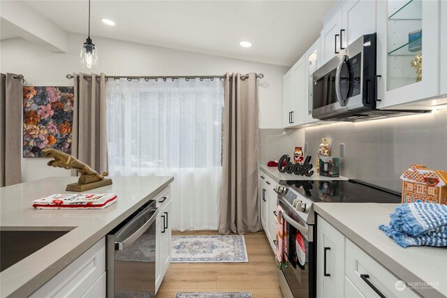 kitchen with white cabinets, stainless steel appliances, lofted ceiling, and light wood-type flooring