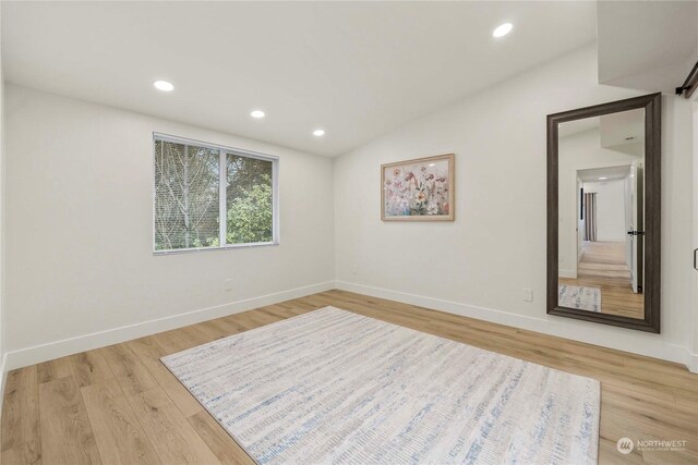 spare room featuring light hardwood / wood-style flooring and lofted ceiling