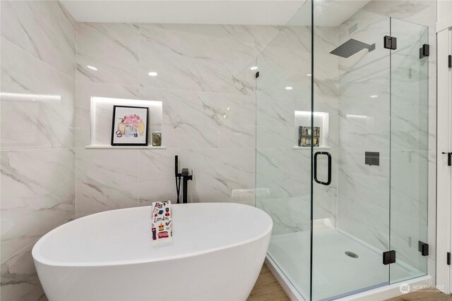 bathroom with tile walls and independent shower and bath