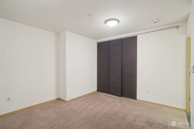 unfurnished bedroom with light colored carpet and a closet