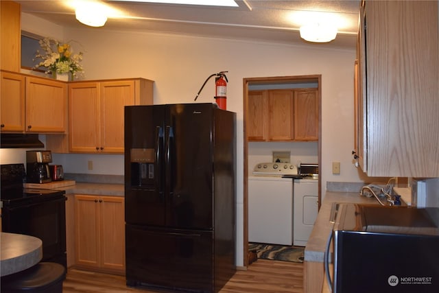 kitchen with light hardwood / wood-style floors, black appliances, crown molding, and washing machine and dryer