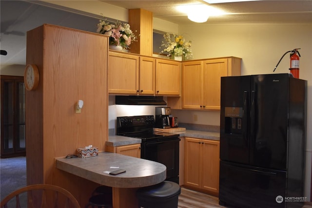 kitchen featuring black appliances, light brown cabinetry, and kitchen peninsula