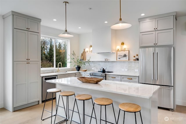 kitchen featuring pendant lighting, custom exhaust hood, sink, and appliances with stainless steel finishes