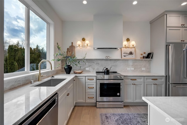 kitchen with stainless steel appliances, light stone counters, plenty of natural light, and sink