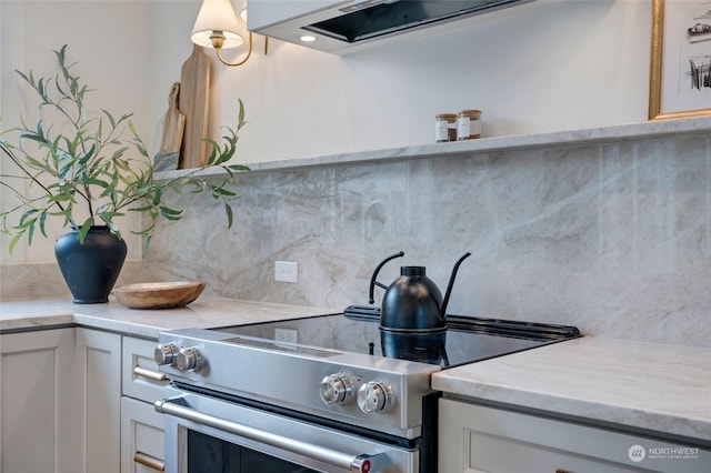 kitchen featuring white cabinets, high end stainless steel range, and tasteful backsplash