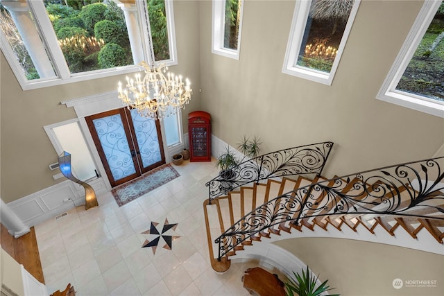 foyer featuring a notable chandelier, light tile patterned flooring, and french doors