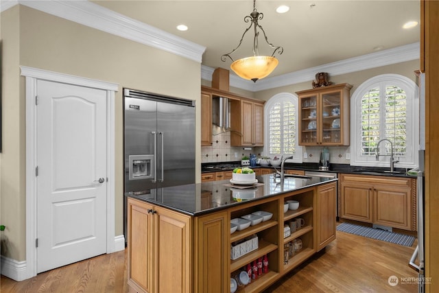 kitchen featuring sink, a center island with sink, decorative light fixtures, and crown molding