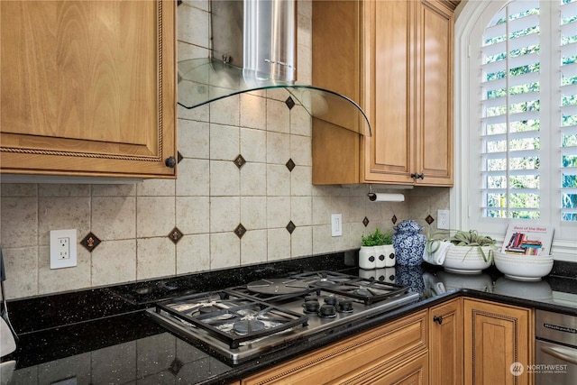 kitchen with dark stone countertops, gas cooktop, exhaust hood, and tasteful backsplash