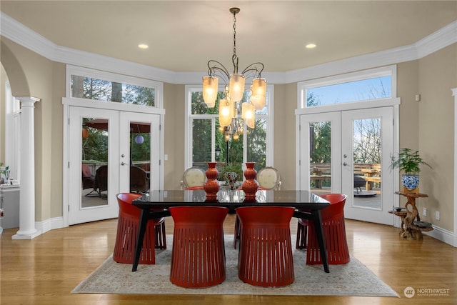 dining room with light hardwood / wood-style flooring, french doors, decorative columns, and a chandelier