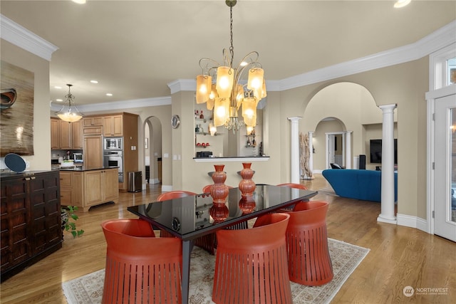 dining space with ornate columns, an inviting chandelier, ornamental molding, and light hardwood / wood-style flooring